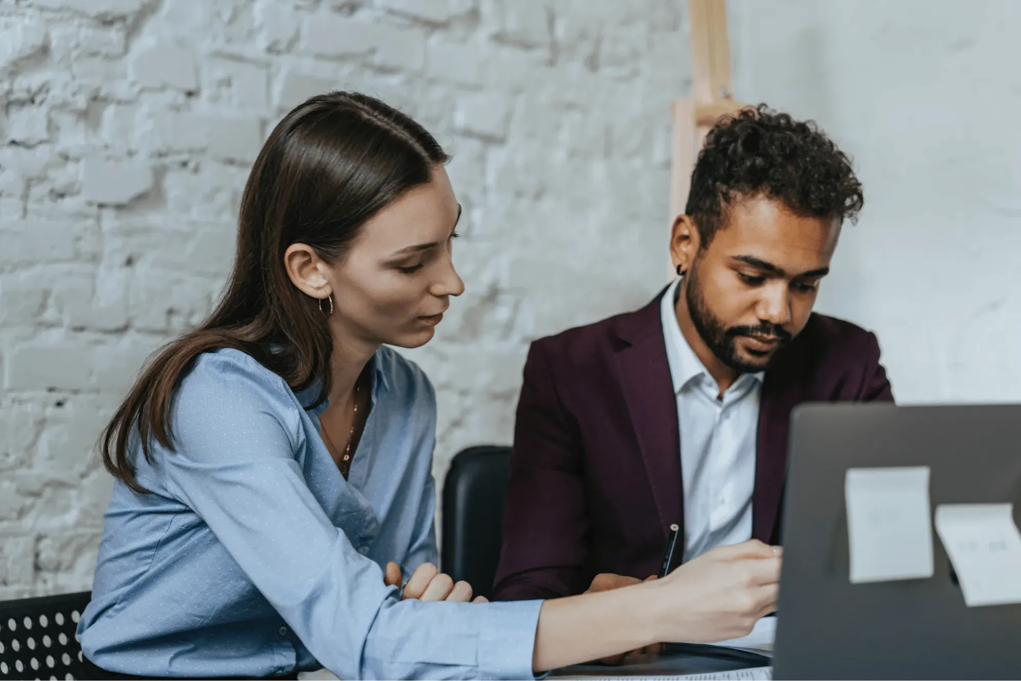 Two people working on laptop managing online exams